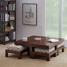 a coffee table with two stools and a book shelf in the corner next to it