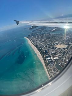 an airplane wing flying over the ocean and land