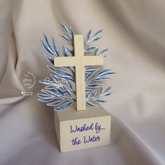 a wooden cross with blue leaves on it and the words unfinished by the water written below