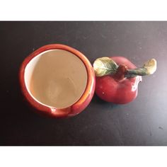 two red apples and a white cup on a black table with one apple in the foreground