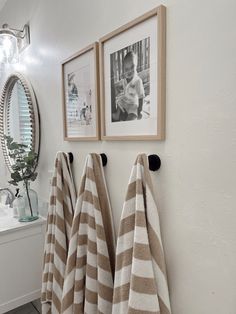 two towels are hanging on the wall in front of a mirror with pictures above it