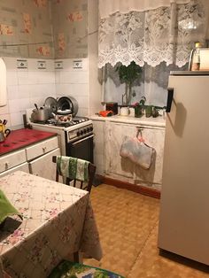 a kitchen with a refrigerator, stove and table covered in cloths next to a window