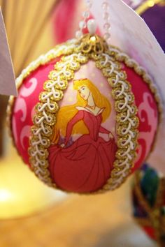 a pink ornament with a princess image on it's side hanging from a string