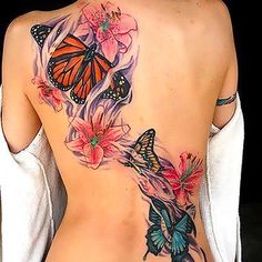 the back of a woman's body with butterflies on it and pink flowers in the middle