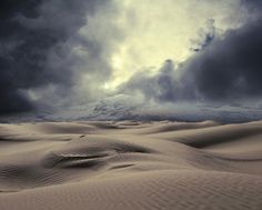 the sky is filled with purple clouds over sand dunes