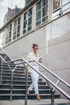 a woman is walking down the stairs while looking at her cell phone