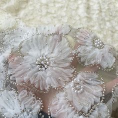 an image of some flowers on a lace fabric material that is white and has beading around the edges