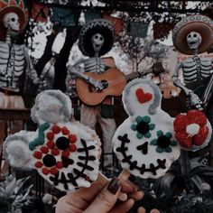 someone is holding up some decorated cookies in the shape of flowers and skeletons with hearts on them