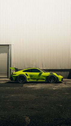 a lime green sports car parked in front of a large metal building with corrugated walls