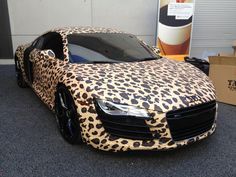 an animal print car is parked in front of a building with boxes on the ground