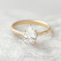 a gold ring with a pear shaped diamond