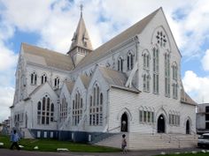 a large white church with steeples and two people walking in front of the building