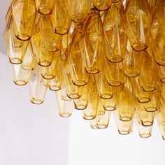 a bunch of yellow wine glasses hanging from a chandelier