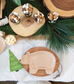 a table topped with plates and cups filled with desserts next to pine cones on top of wooden trays