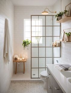 a bathroom with white tile walls and flooring, including a shower door that leads to the toilet