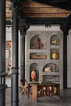 a room with several shelves and sculptures on the wall, including an antique desk in between two columns