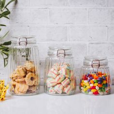 three glass jars filled with candy and cookies