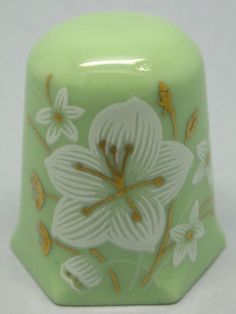 a green vase with white flowers painted on it