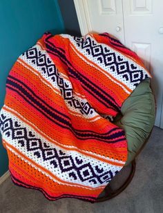 an orange and black blanket sitting on top of a wooden chair next to a door