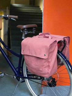 a pink bag sitting on the back of a bike in front of an orange wall