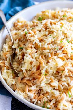 a white bowl filled with rice on top of a blue and white table cloth