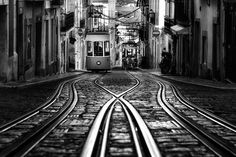 a black and white photo of a trolley going down the tracks in an alleyway