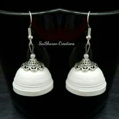 a pair of white earrings on a black background