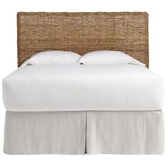 a bed with white linens and wicker headboard