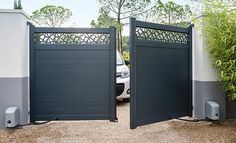 a car is parked in the driveway behind two gates that are open to reveal an entrance