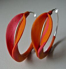 pair of orange and pink hoop earrings on white surface with silver earwires, closeup