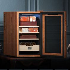 an open wooden cabinet with many items in it next to a clock on a table