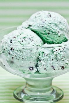 two scoops of ice cream in a glass bowl on a green and white tablecloth