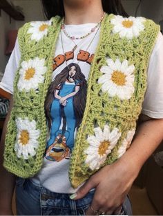 a woman wearing a green crocheted vest with white flowers on the front and back