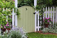 a white picket fence with potted plants and flowers around it