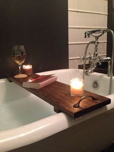 a candle is sitting on top of a bathtub next to a glass of wine