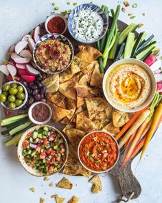 a platter filled with dips, crackers and veggies is shown