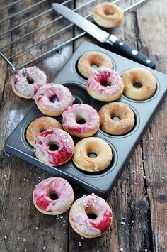 several donuts in a muffin tin with frosting and sprinkles