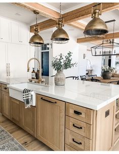 a large kitchen with an island in the middle and two pendant lights hanging from the ceiling