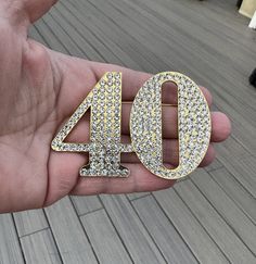 a hand holding a gold and diamond forty birthday pin