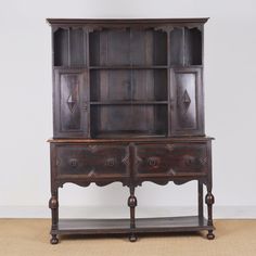 an old wooden hutch with two drawers and one door on the front, sitting against a white wall