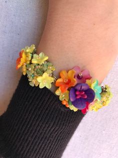 Pretty Petunia bracelet made with a stunning color mix of deep purple, yellow, orange and a pretty greeny turquoise. Made with an assortment of glass bead and handpainted resin flowers, it is meticulously sewn together by hand. This is just a really lovely piece and matches beautifully with our other pieces shown in Petunia. This is a quality piece of jewelry that will last a life time. Created by designer Colleen Toland who has been creating her unique style of vintage jewelry for more than 30 Colorful Beaded Flower Jewelry, Handmade Vibrant Beaded Bracelets, Handmade Rainbow Flower Jewelry, Multicolor Resin Bead Jewelry, Unique Multicolor Flower Bracelet, Whimsical Multicolor Bracelet Jewelry, Vibrant Yellow Beaded Bracelets As Gift, Handmade Multicolor Resin Bracelets, Whimsical Multicolor Flower Jewelry