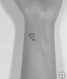 a small heart and an arrow tattoo on the left inner wrist is shown in black ink