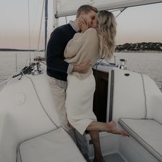 a man and woman kissing on the back of a boat