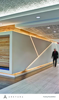 a man is walking through an empty building with wood paneling on the walls and ceiling