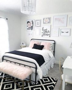 a black and white bedroom with pictures on the wall above the bed, along with a pink fluffy rug