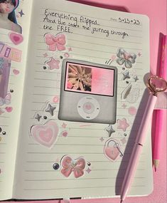 an open notebook with pink stickers on it and a pen sitting next to it