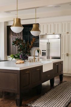 the kitchen is clean and ready to be used for cooking or baking, with gold pendant lights hanging over the island