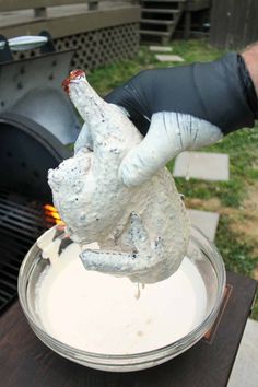 a person is cooking food on the grill with gloves over their arm and gloved hand