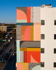 a large building with many different colored designs on it's side and the sky in the background