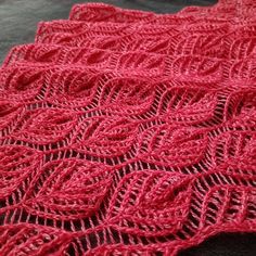 a red knitted blanket sitting on top of a bed